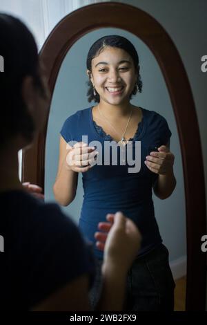 Biracial adolescente rit de Hersef dans le miroir Banque D'Images