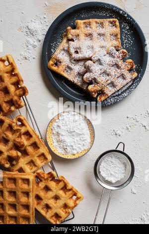 Gaufres avec sucre en poudre sur assiette gris foncé Banque D'Images