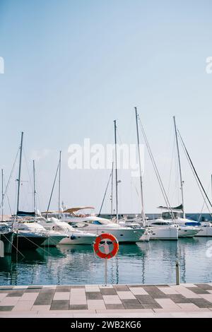 Bouée de sauvetage rouge se dresse sur un stand sur la jetée sur le fond de yachts amarrés Banque D'Images