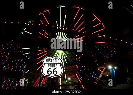 Photo de nuit du célèbre panneau route 66 devant la grande roue, tout illuminé. Santa Monica Pier, Los Angeles, Californie, États-Unis Banque D'Images