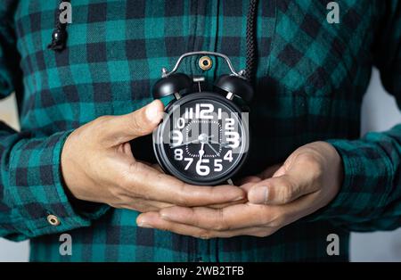 Main d'homme tenant un réveil noir. il est temps de se réveiller Banque D'Images