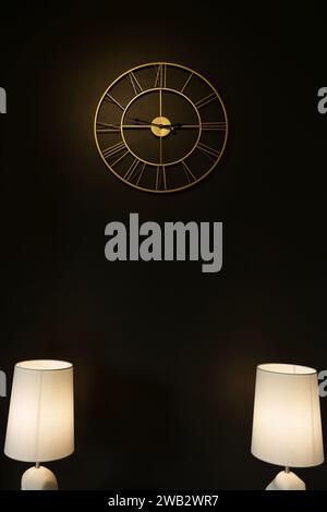 Une horloge montée sur le mur au-dessus de deux lampes Banque D'Images