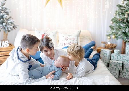 Famille heureuse, nouveau-né et frères aînés, maman à la maison à Noël Banque D'Images