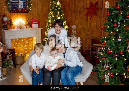 Famille heureuse, nouveau-né et frères aînés, maman à la maison à Noël Banque D'Images