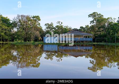 Maisons en bois sur pilotis se reflétant dans le fleuve Amazone, état d'Amazonas, Brésil Banque D'Images