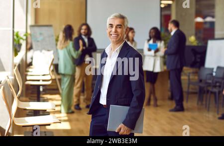 Heureux homme d'affaires mature regardant la caméra et souriant dans le bureau. Banque D'Images