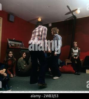 Teenage party dans les années 70. Un groupe d'adolescents ont organisé une fête et un garçon et une fille est de danse à la musique de la jukebox. L'avis de large jeans pattes type qui était typique de la décennie. La Suède des années 1970. Kristoffersson Photo Banque D'Images