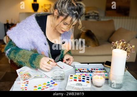 Photo de jeune femme à la maison appréciant peindre des aquarelles à la maison dans la détente Banque D'Images