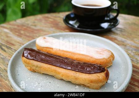 Assiette de chocolat et vanille Eclairs avec une tasse de café chaud en toile de fond Banque D'Images