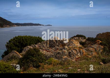 Montagnes et rochers couverts par une végétation fraîche, entourant une baie de la mer Méditerranée. Ciel nuageux au début du printemps. Au sud de la Sardaigne, Domus de Banque D'Images