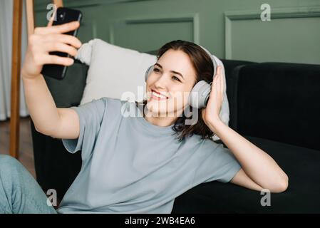 Une jeune femme joyeuse portant des écouteurs sans fil écoutant de la musique. Musique Bliss. Joyeuse jeune femme immergée dans des mélodies avec des écouteurs sans fil Banque D'Images