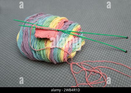 arc-en-ciel de l'année et aiguilles à tricoter vertes, projet de tricot fait à la main Banque D'Images