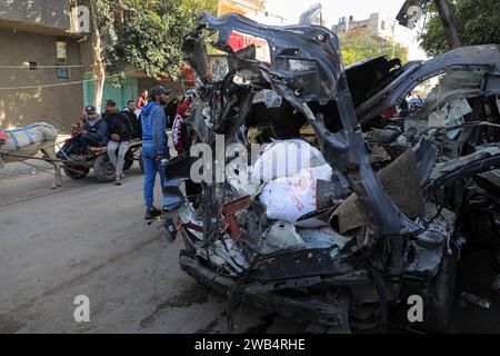 Gaza. 8 janvier 2024. Les gens regardent un véhicule détruit lors d’une frappe aérienne israélienne dans la ville de Rafah, dans le sud de la bande de Gaza, le 8 janvier 2024. Le bilan palestinien des attaques israéliennes en cours sur la bande de Gaza a dépassé 23 000 morts, a déclaré lundi le ministère de la Santé basé à Gaza. Crédit : Rizek Abdeljawad/Xinhua/Alamy Live News Banque D'Images