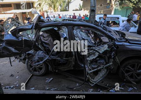 Gaza. 8 janvier 2024. Les gens regardent un véhicule détruit lors d’une frappe aérienne israélienne dans la ville de Rafah, dans le sud de la bande de Gaza, le 8 janvier 2024. Le bilan palestinien des attaques israéliennes en cours sur la bande de Gaza a dépassé 23 000 morts, a déclaré lundi le ministère de la Santé basé à Gaza. Crédit : Rizek Abdeljawad/Xinhua/Alamy Live News Banque D'Images