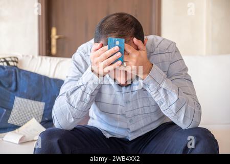 homme détenant une carte bancaire tout en se sentant stressé en raison d'un problème financier Banque D'Images