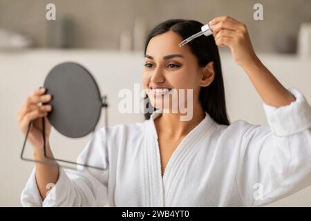 Belle dame indienne appliquant le sérum de visage avec compte-gouttes Banque D'Images