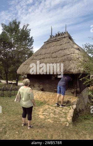 Touristes nez dans un petit chalet au toit de chaume dans le vieux village du musée en plein air, Sirogojno, Serbie Banque D'Images