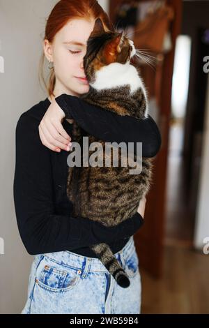 Photo d'intérieur d'une dame incroyable tenant un animal de compagnie. Portrait de femme tenant le chat rayé mignon avec les yeux verts. Banque D'Images