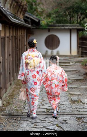 Deux filles portant un kimono traditionnel japonais marchant dans la rue. Kyoto, Japon. Banque D'Images