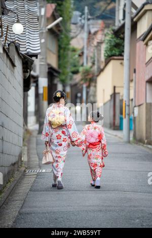 Deux filles portant un kimono traditionnel japonais marchant dans la rue. Kyoto, Japon. Banque D'Images