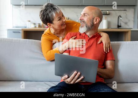 Heureux couple senior avec ordinateur portable ayant du plaisir ensemble à la maison Banque D'Images