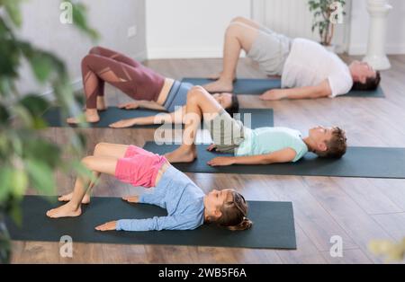 Maman, papa, fille et fils pratique le yoga do Bridge pose, Sarvangasana Banque D'Images