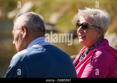 Couple âgé trouvant réconfort et joie alors qu'ils se reposent sur un banc de parc, engagés dans une conversation sincère, après un strol rajeunissant dont un témoignage Banque D'Images