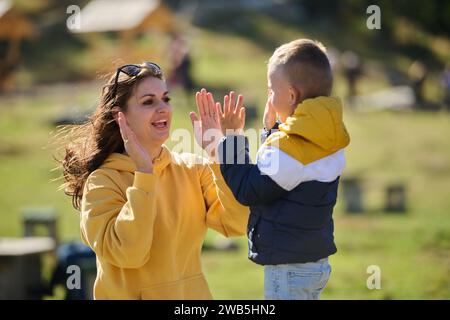 Une mère et son fils créent des souvenirs chéris alors qu'ils s'engagent de manière ludique dans des activités de plein air, leurs rires faisant écho à la joie des moments partagés et de la Banque D'Images