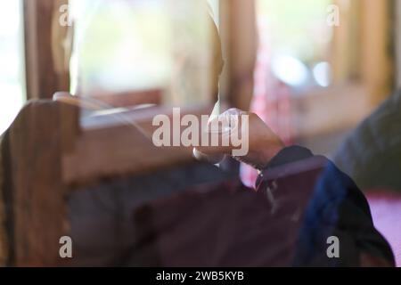 Capturé à travers la lentille douce d'une fenêtre, un homme âgé profite d'un moment tranquille de réflexion et de solitude au petit matin, en sirotant son café Banque D'Images