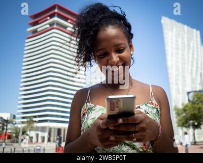 Jeune femme afro-américaine insouciante bavardant dans une ville en été Banque D'Images