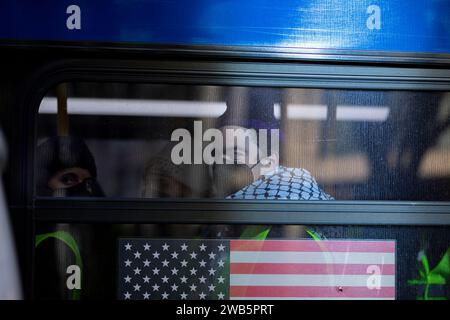 NEW YORK, NEW YORK - JANVIER 8 : des manifestants pro-palestiniens arrêtés sont assis dans un bus après avoir bloqué l'entrée du Holland tunnel en direction du New Jersey dans le Lower Manhattan le 8 janvier 2024 à New York. La manifestation faisait partie d'une série d'actions coordonnées qui ont eu lieu simultanément à trois autres principaux points de passage de New York, y compris le pont de Brooklyn, le pont de Manhattan et le pont de Williamsburg, où plus de 300 personnes ont été arrêtées et la circulation a été bloquée pendant des heures. (Photo de Michael Nigro/Sipa USA) Banque D'Images