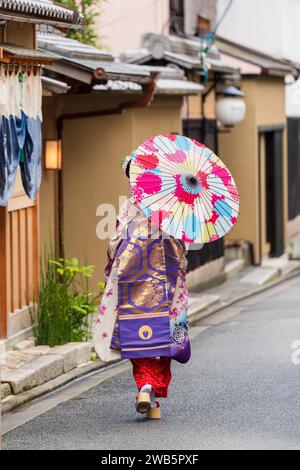 Geisha tenant un parapluie en papier marchant dans la rue à Gion Kyoto, Japon. Banque D'Images