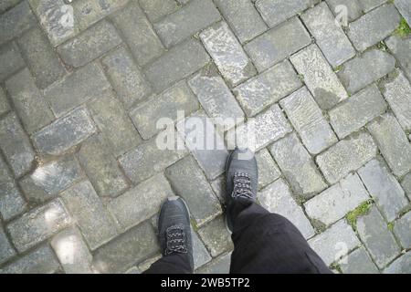 Homme pieds nus marchant sur la route pavée de bloc. Banque D'Images