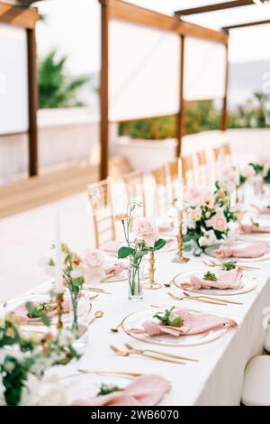 Des bouquets de fleurs se dressent sur une longue table de fête près des bougies et des petites grenades sur des assiettes Banque D'Images