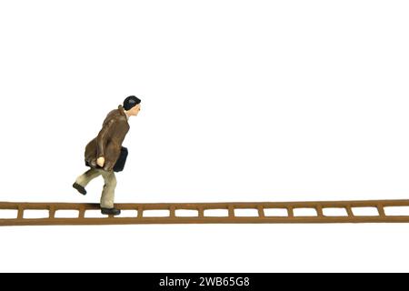 Photographie miniature de figurine de jouet de personnes. Illustration du concept d'escalier de carrière de succès. Un homme d'affaires courant au-dessus de l'échelle en bois, isolé sur le fond blanc Banque D'Images