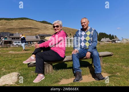 Couple âgé trouvant réconfort et joie alors qu'ils se reposent sur un banc de parc, engagés dans une conversation sincère, après un strol rajeunissant dont un témoignage Banque D'Images