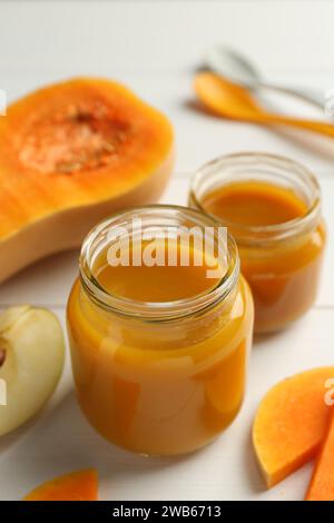 Nourriture savoureuse pour bébé dans des pots et des ingrédients sur la table blanche, gros plan Banque D'Images