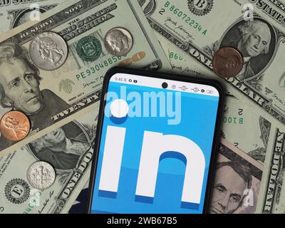 Bavière, Allemagne - 9 janvier 2024 : dans cette illustration photo, un logo Linkedin affiché sur un smartphone avec des billets de dollar américain et des coi Banque D'Images