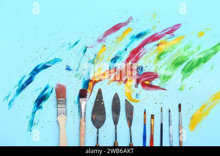 Pinceaux d'artiste, couteaux de palette et peintures sur fond bleu Banque D'Images