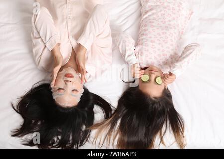 Mère asiatique avec sa petite fille se relaxant sur le lit, vue de dessus Banque D'Images