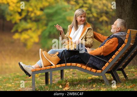 Couple senior affectueux avec des feuilles sèches passant du temps ensemble dans le parc d'automne Banque D'Images