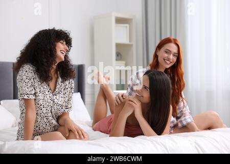 Heureux jeunes amis passant du temps ensemble sur le lit à la maison Banque D'Images