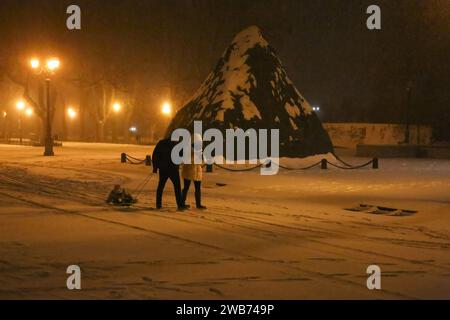 Odessa, Ukraine. 08 janvier 2024. Des personnes avec un enfant en traîneau passent devant le monument au duc de Richelieu dans des structures de protection lors d'une tempête de neige sur le boulevard Primorsky. A Odessa, à partir de l’heure du déjeuner le 08 janvier 2024, le temps s’est fortement détérioré, la pluie s’est transformée en neige et la température a chuté. À cet égard, les autorités municipales ont demandé aux habitants de la ville de limiter, si possible, les déplacements dans la ville à pied et en voiture et de transférer les travailleurs vers le travail à distance. Crédit : SOPA Images Limited/Alamy Live News Banque D'Images