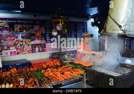 Un thaïlandais grillant du poulet dans une petite cuisine de rue sur soi Naradhiwas Rajanagarindra à Bangkok, Thaïlande. Banque D'Images