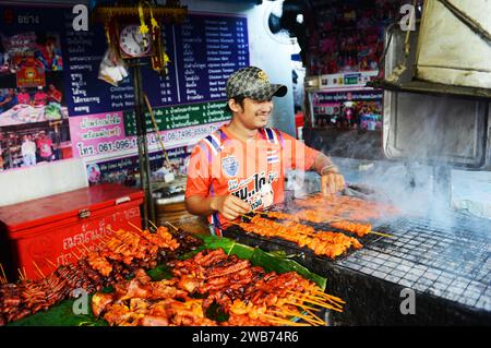 Un thaïlandais grillant du poulet dans une petite cuisine de rue sur soi Naradhiwas Rajanagarindra à Bangkok, Thaïlande. Banque D'Images