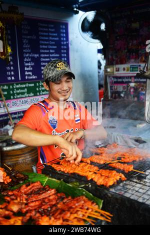 Un thaïlandais grillant du poulet dans une petite cuisine de rue sur soi Naradhiwas Rajanagarindra à Bangkok, Thaïlande. Banque D'Images