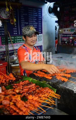 Un thaïlandais grillant du poulet dans une petite cuisine de rue sur soi Naradhiwas Rajanagarindra à Bangkok, Thaïlande. Banque D'Images