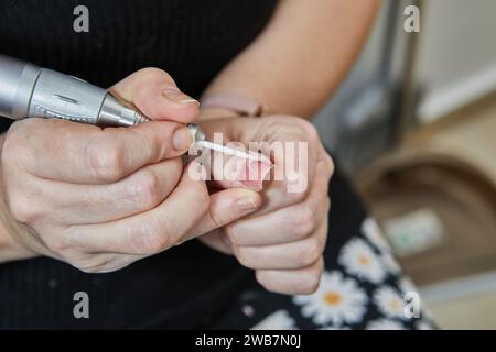 Témoin de l'expertise d'un technicien d'ongles comme ils appliquent habilement des extensions d'ongles de gel, polir les ongles savamment, et utiliser une machine de manucure à crea Banque D'Images