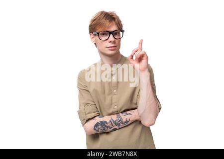 inspiré par l'idée d'un jeune homme aux cheveux rouges dans une chemise beige porte des lunettes pour la vision sur un fond blanc Banque D'Images