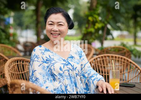 Portrait de femme âgée souriante prenant des boissons au café en plein air Banque D'Images